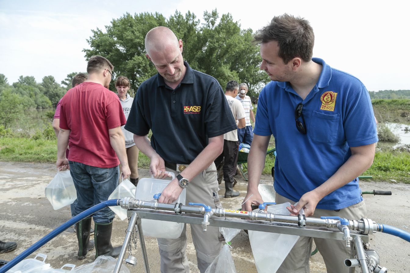 Vom Hochwasser betroffenen Menschen versorgen sich mit Trinkwasser vom ASB.